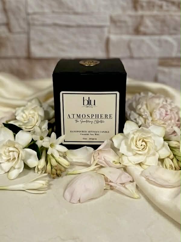 Blu Atmosphere candle surrounded by white flowers on a textured surface