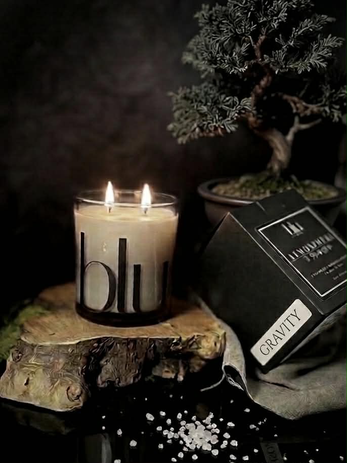 A lit Gravity artisan candle on a modern desk, providing a grounded home fragrance to help focus and quiet the chaos