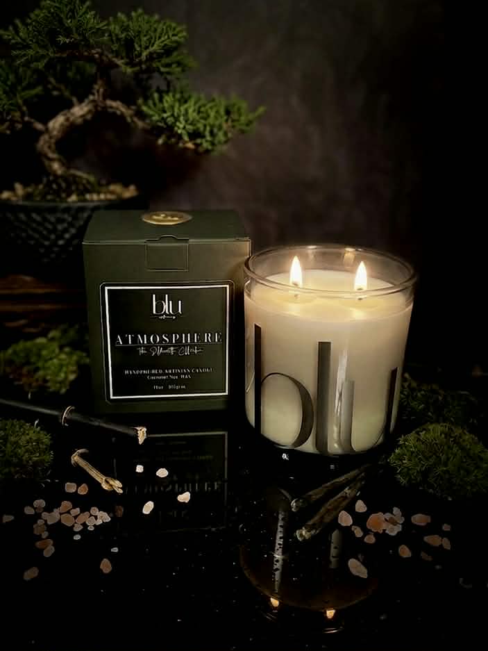 Lit candle with 'blu' branding next to a decorative box on a dark surface. petrichor candle earthy candle